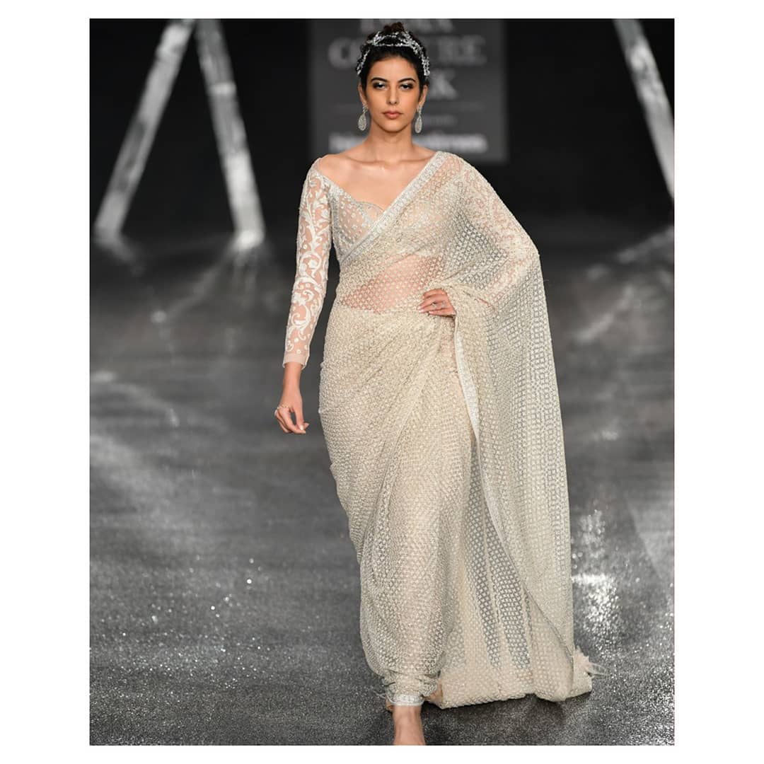 The embroidered, ivory sari by Falguni Shane Peacock is paired with a full-sleeved embellished blouse with a wide neck
