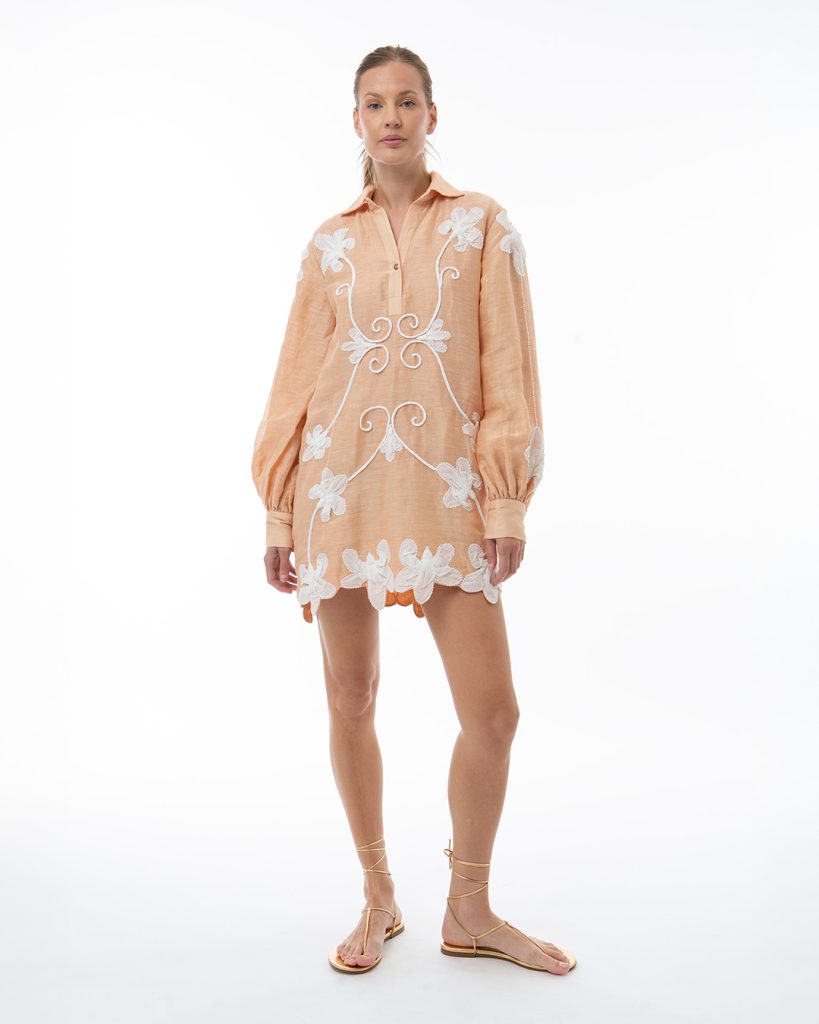 Woman in peach tunic dress with large white embroidery