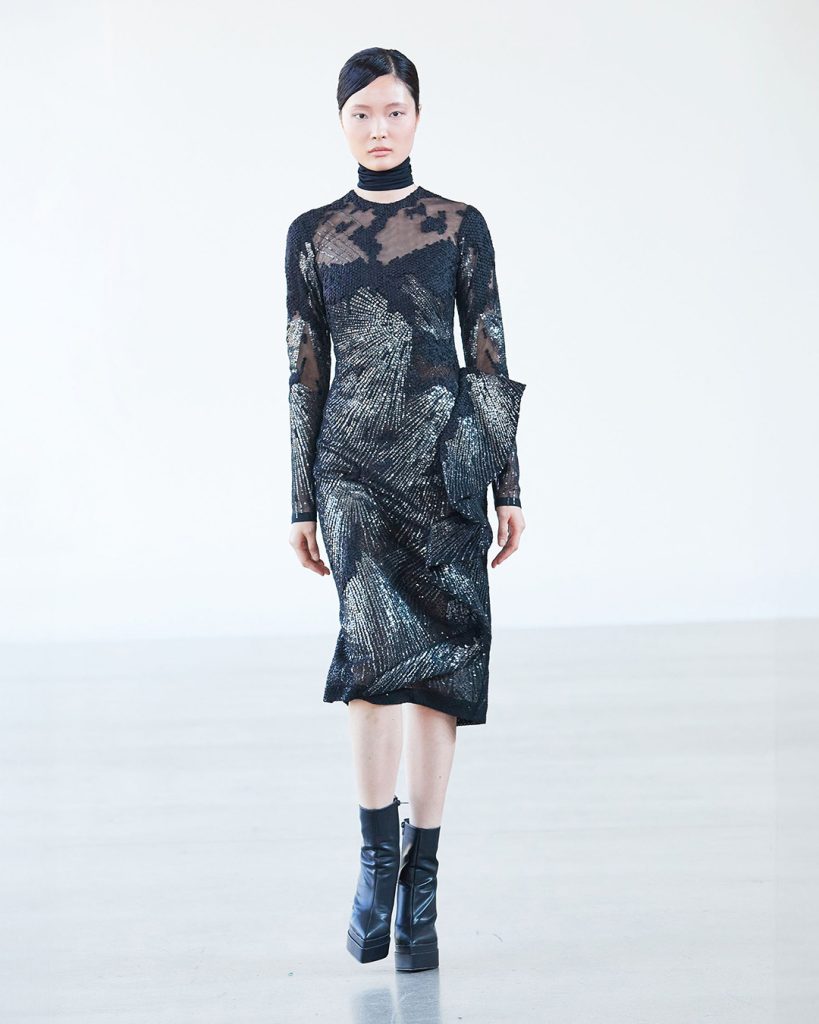 Model walking in a black and gunmetal sheer long dress