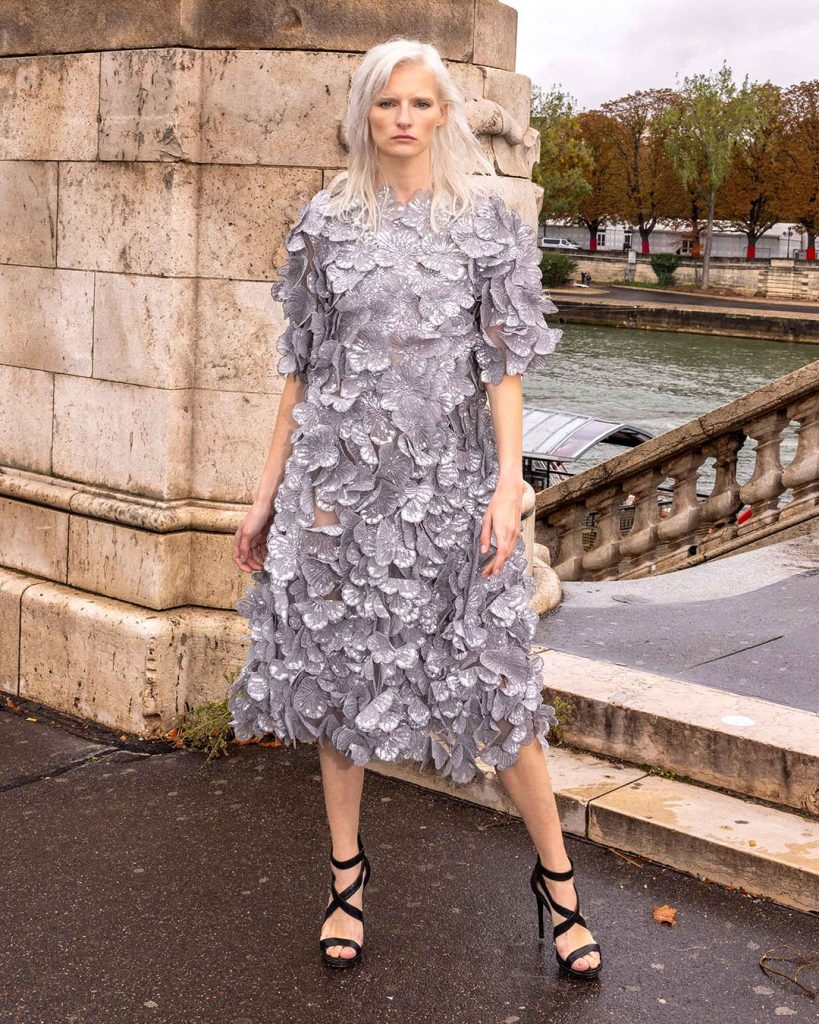 Model wearing a grey midi dress covered in large petal-like sequins